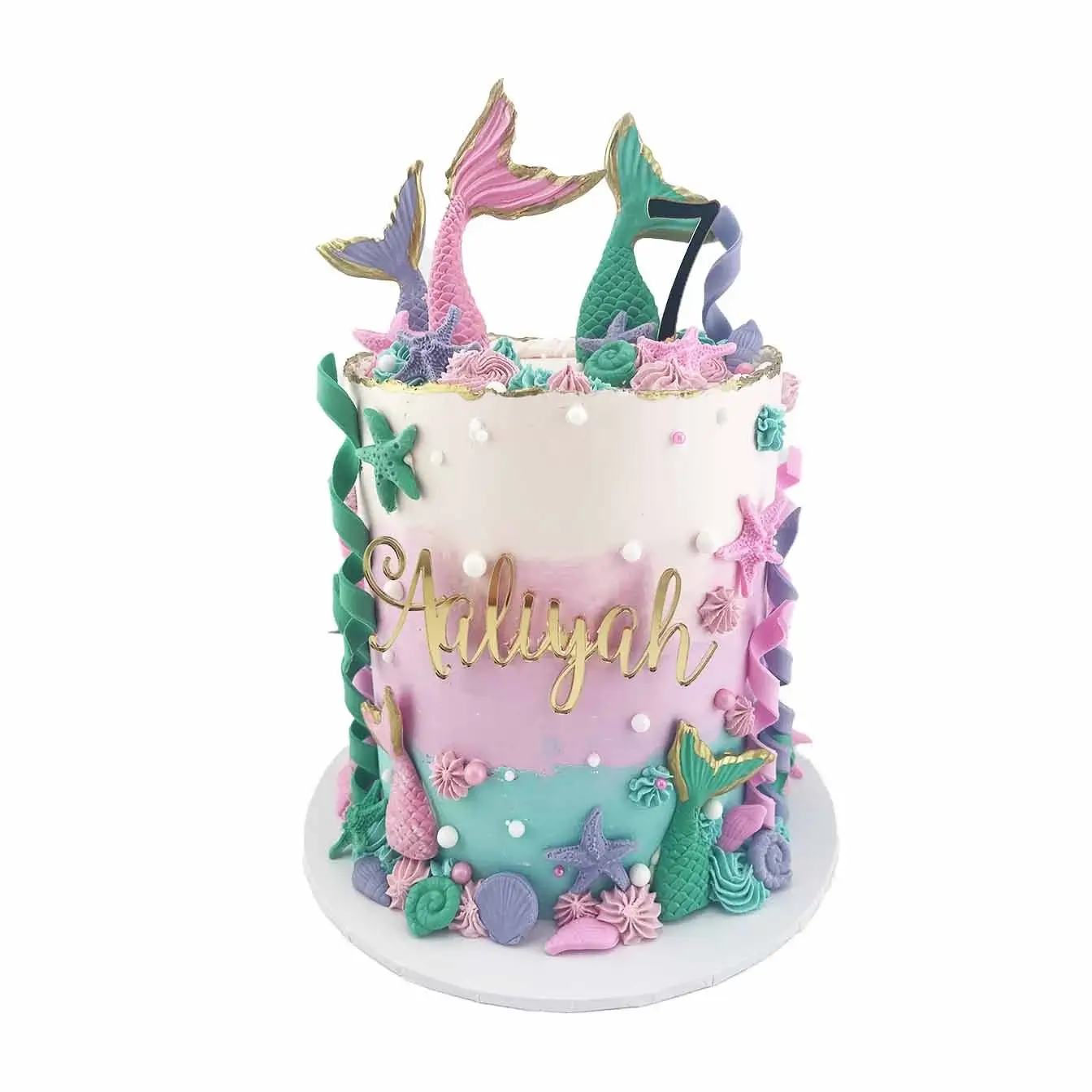 Enchanting Mermaid Dreams Cake - A tall cake in shades of pink, purple, and teal, featuring piped features, sprinkles, moulded mermaid tails, and under the sea shells and coral, a captivating centerpiece that transports you to a magical underwater world.