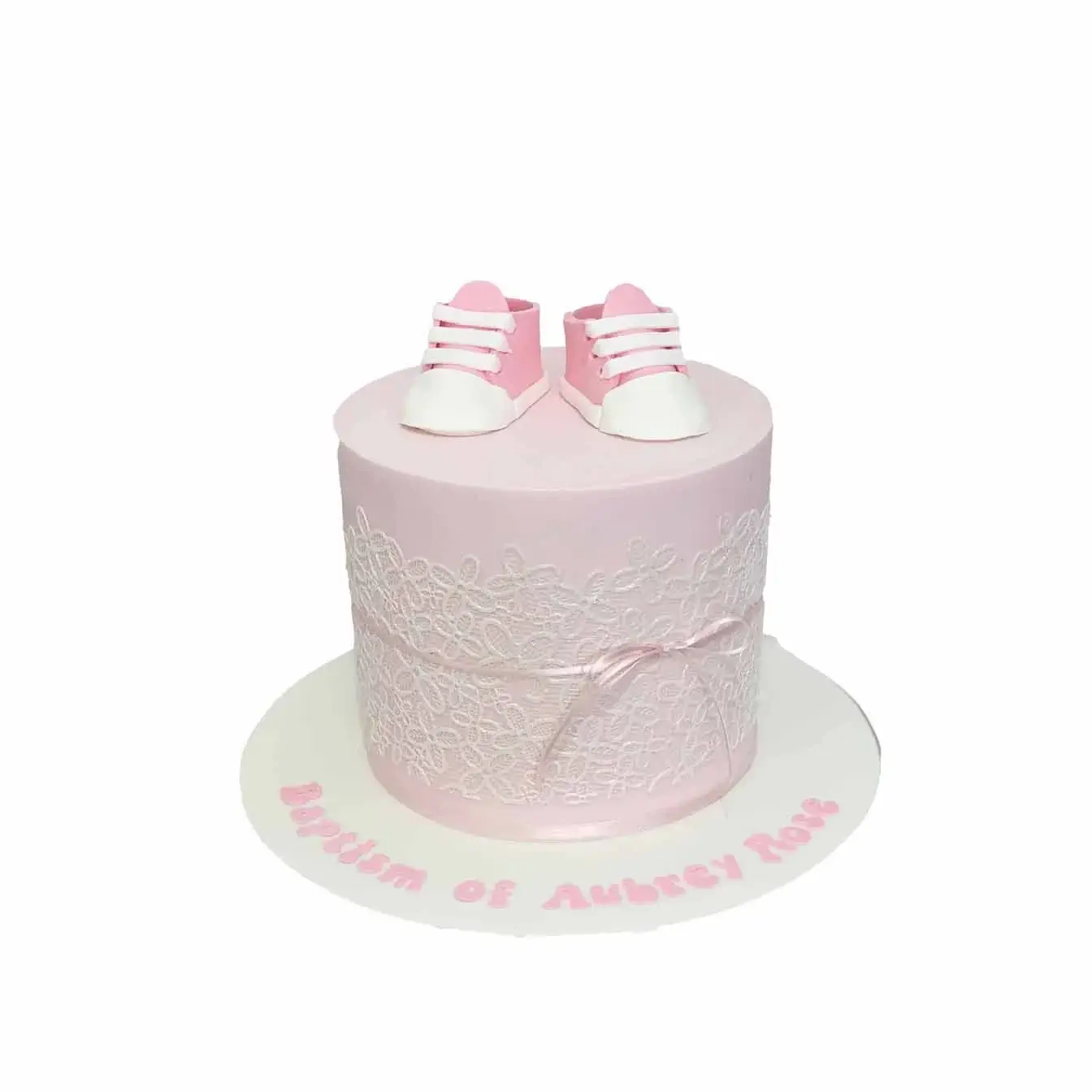 Pink Blessings Baptism Cake - A pink cake with white edible lace and adorable pink baby booties on top, a beautiful centerpiece for a baptism filled with love and blessings.