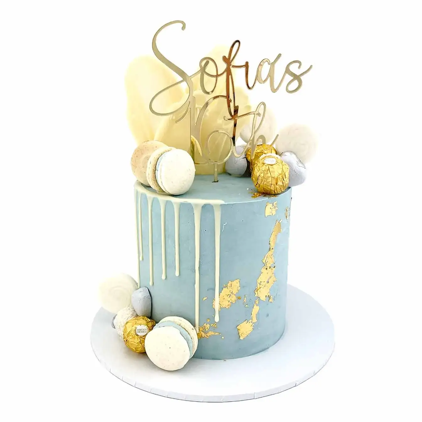  Luxe Drip Cake - A mesmerizing blue and white drip cake with gold leafing, Ferrero Rochers, chocolate sails, macarons, assorted chocolates, and a gold custom cake topper, an opulent centerpiece for indulgent celebrations.