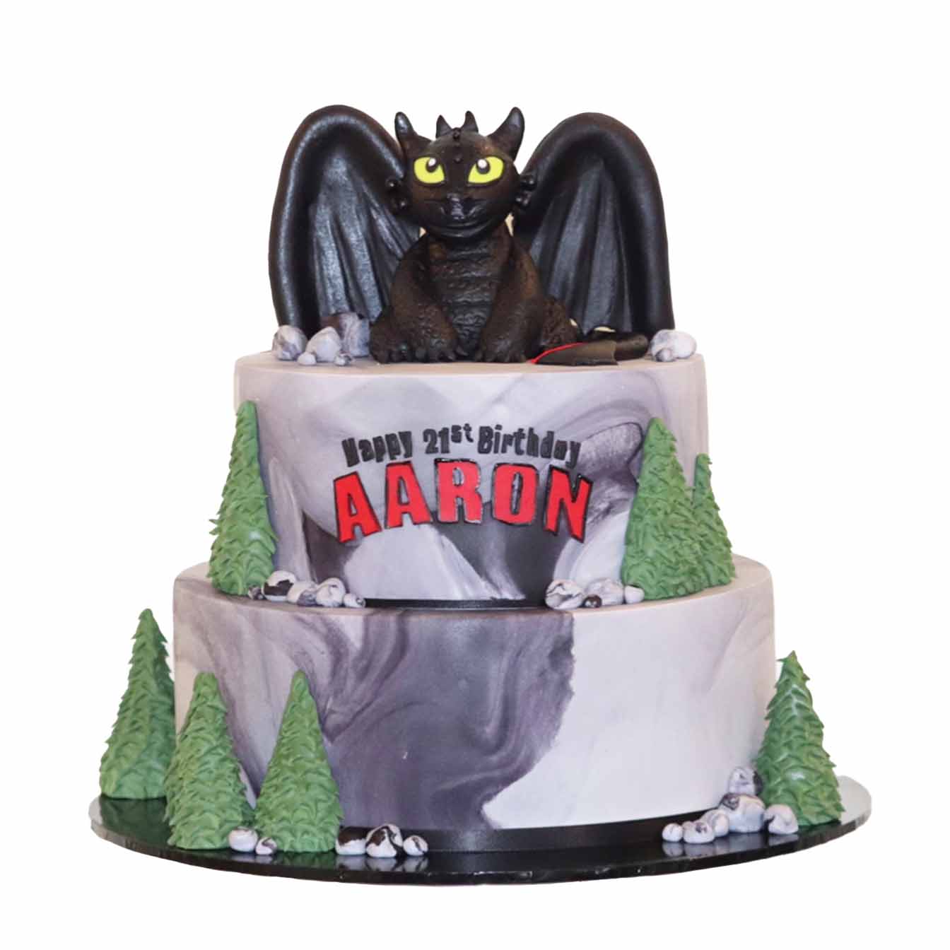 Dragon's Lair Adventure Cake - A cake with marbled rock-like fondant tiers, 3D trees, and a moulded Toothless dragon on top, bringing the magic of 'How to Train Your Dragon' to life.