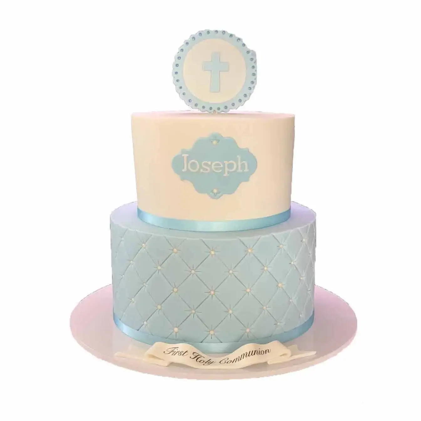 Heavenly Blue Communion Cake - A two-tier cake with a light blue quilted base tier, a white top tier with a name plaque and cross on top, a refined and meaningful centerpiece for Holy Communion celebrations.