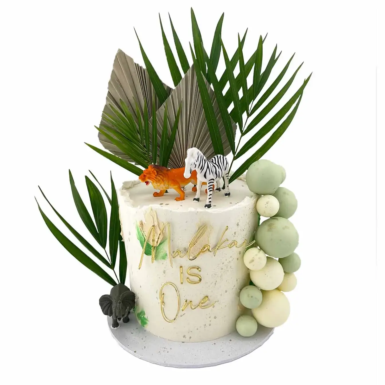 Jungle Adventure Cake with White Base, Green Accents, Gold Splatter, Malakai Topper, Animal Toys, Chocolate Spheres, and Jungle Leaves