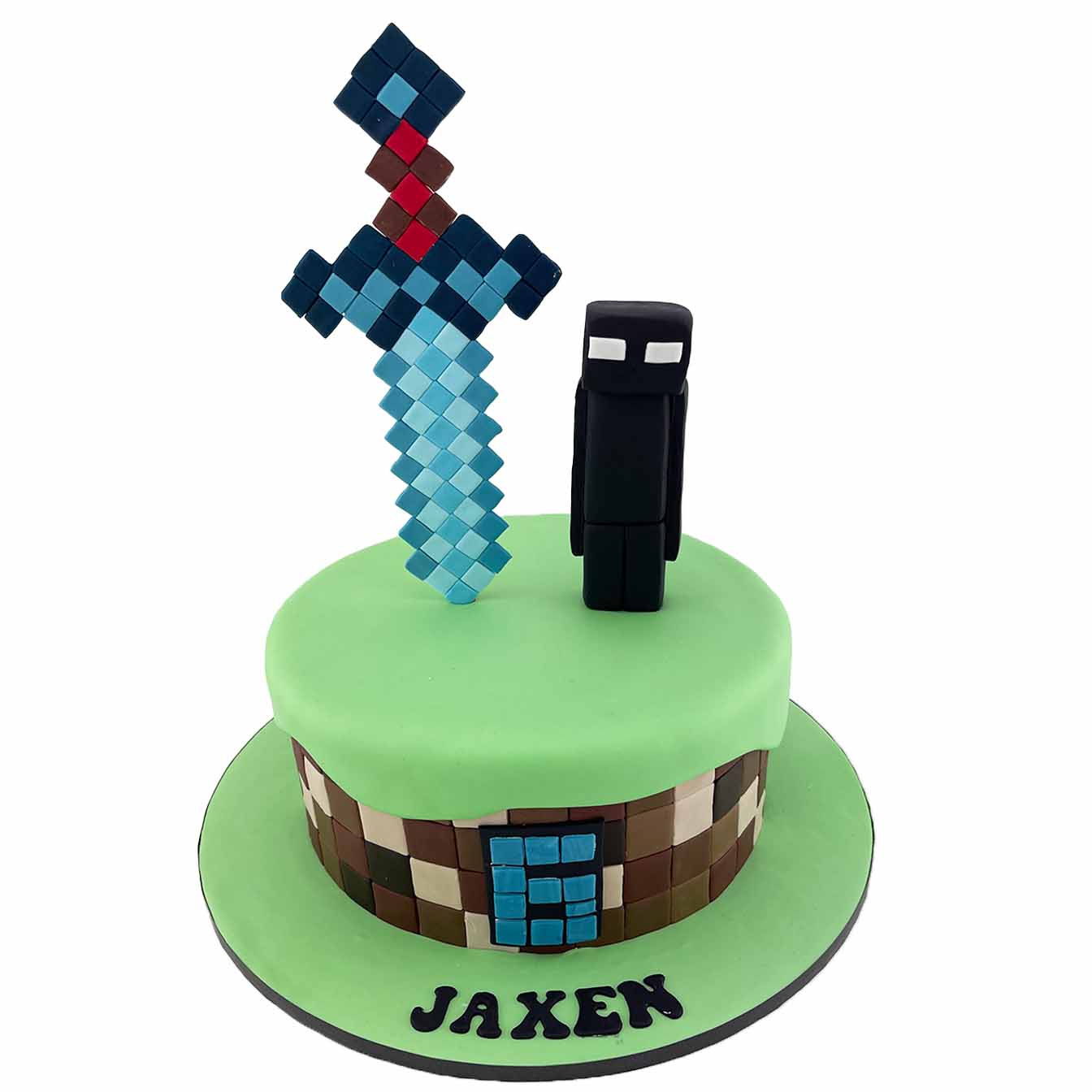 Minecraft Adventure Cake - A 1-tier cake with Minecraft squares, a blue moulded sword, and a menacing Ender-man, a captivating centrepiece for gamers and Minecraft enthusiasts.